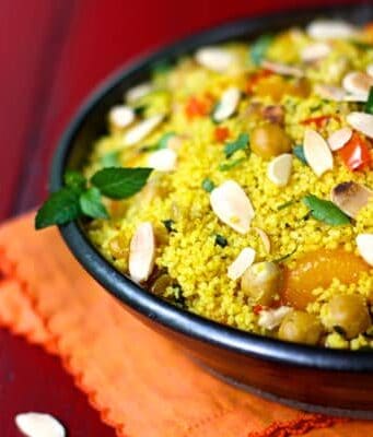 a bowl of orange couscous with almonds and chickpeas