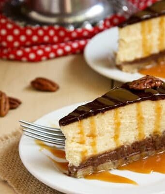 two slices of Turtle Pecan Cluster Cheesecake drizzled with caramel
