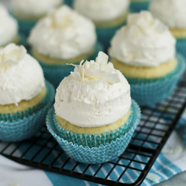coconut cupcakes with coconut frosting on a cooling rack