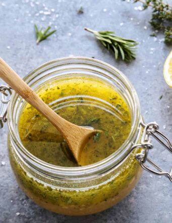 a clear jar of herby lemon vinaigrette