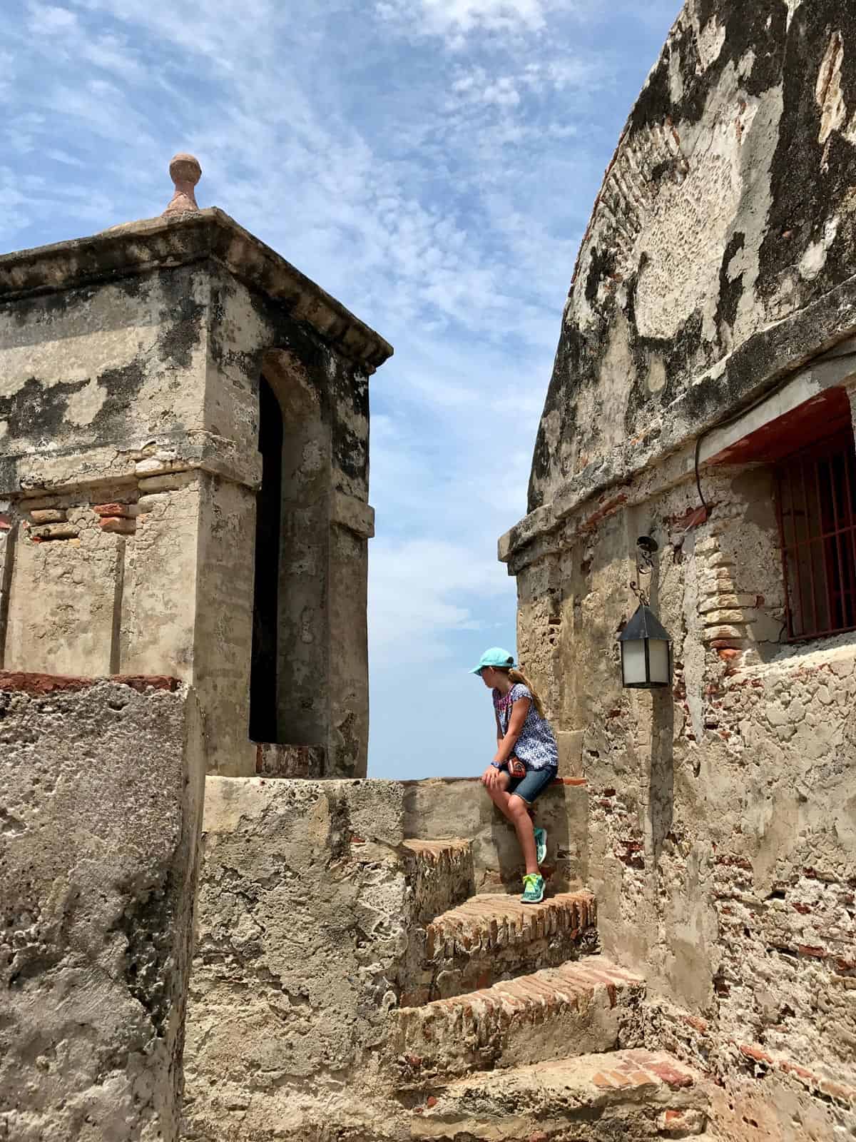 a girl sitting on steps at Castillo de San Felipe de Barajas in Cartagena, Colombia