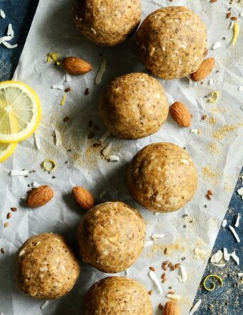 Aloha Protein Balls on parchment paper with almonds, lemon slices and coconut