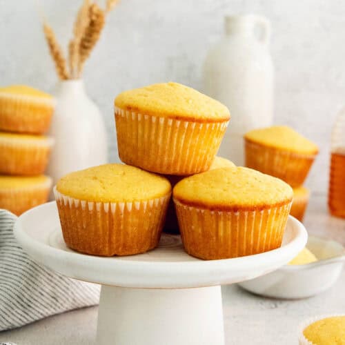 Three honey cornbread muffins on a cake stand.