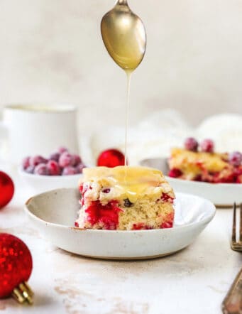 butter cream sauce being spooned over a piece of cranberry cake