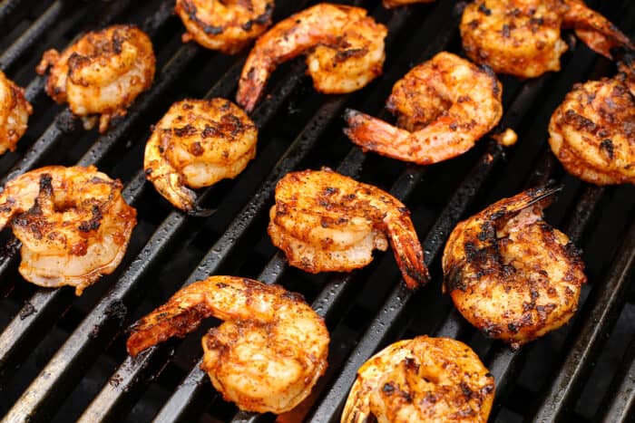 Seasoned shrimp cooking on a grill.