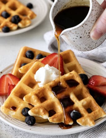 pouring syrup over waffles made with yeast
