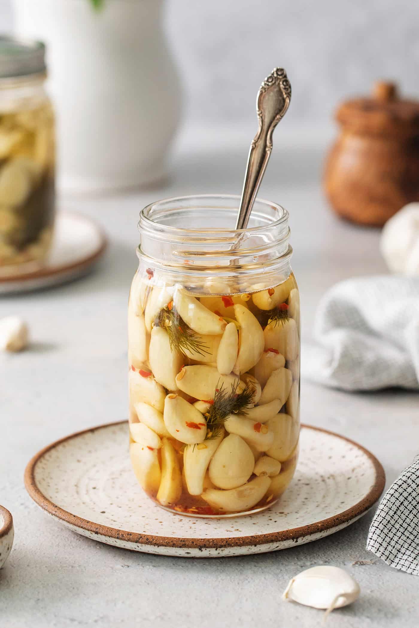 A spoon in a jar of pickled garlic cloves