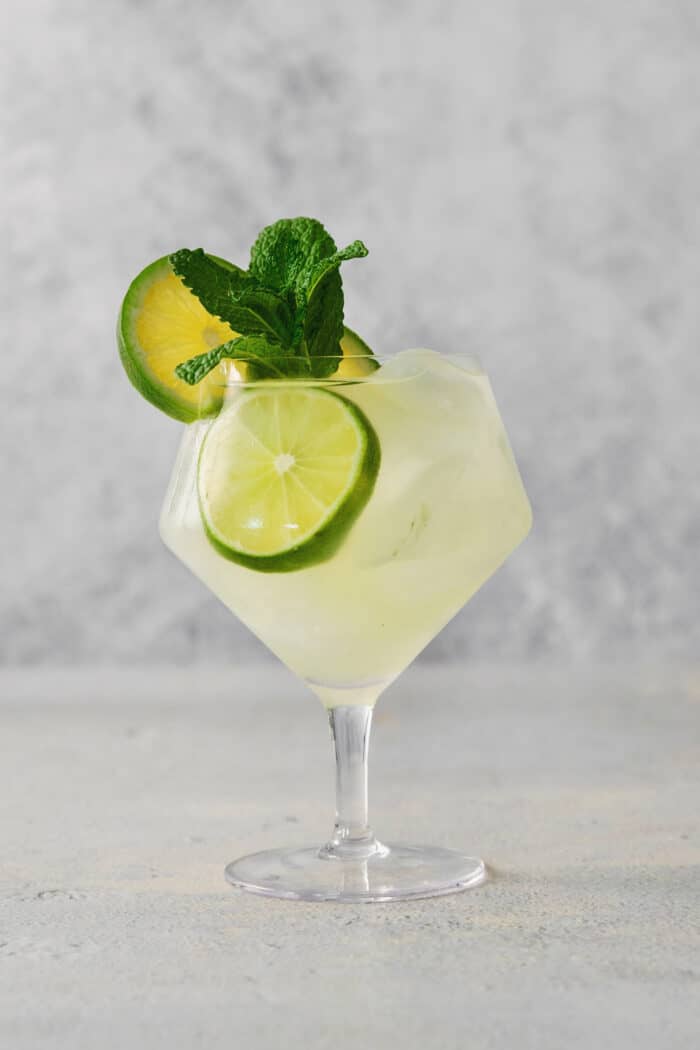 A mojito is shown in a glass topped with mint and lime.