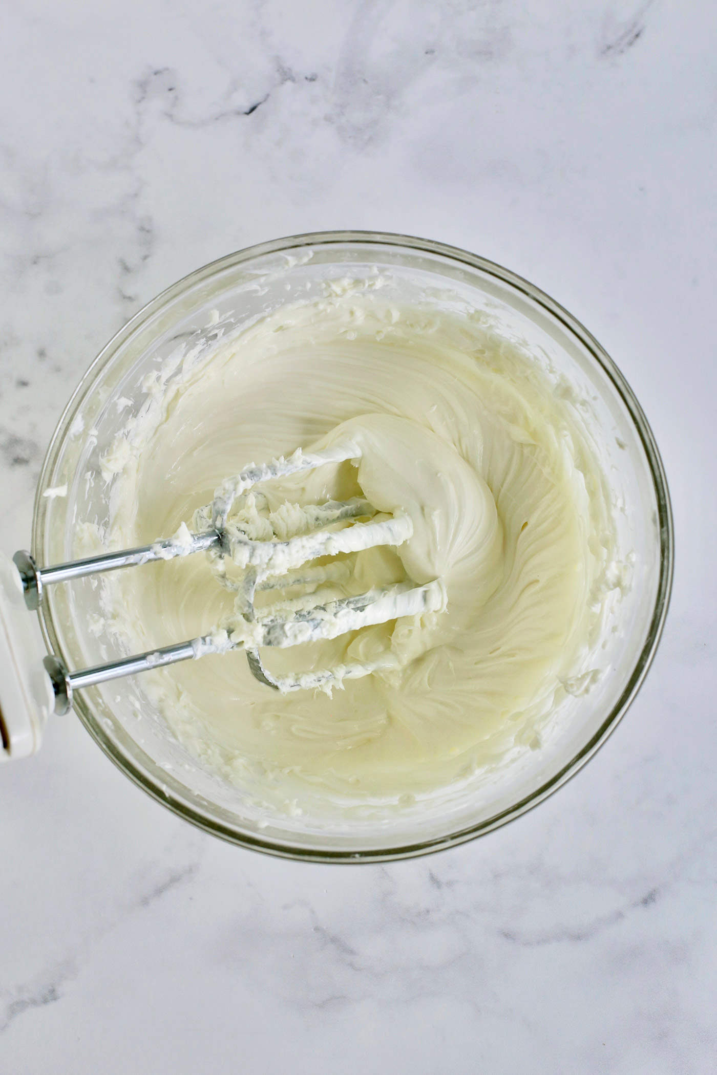 a clear bowl of whipped cream cheese, sugar, and vanilla