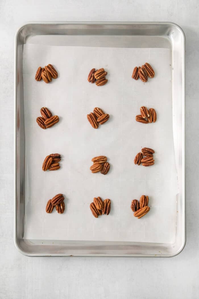 Pecans are shown arranged into clusters on a baking tray.