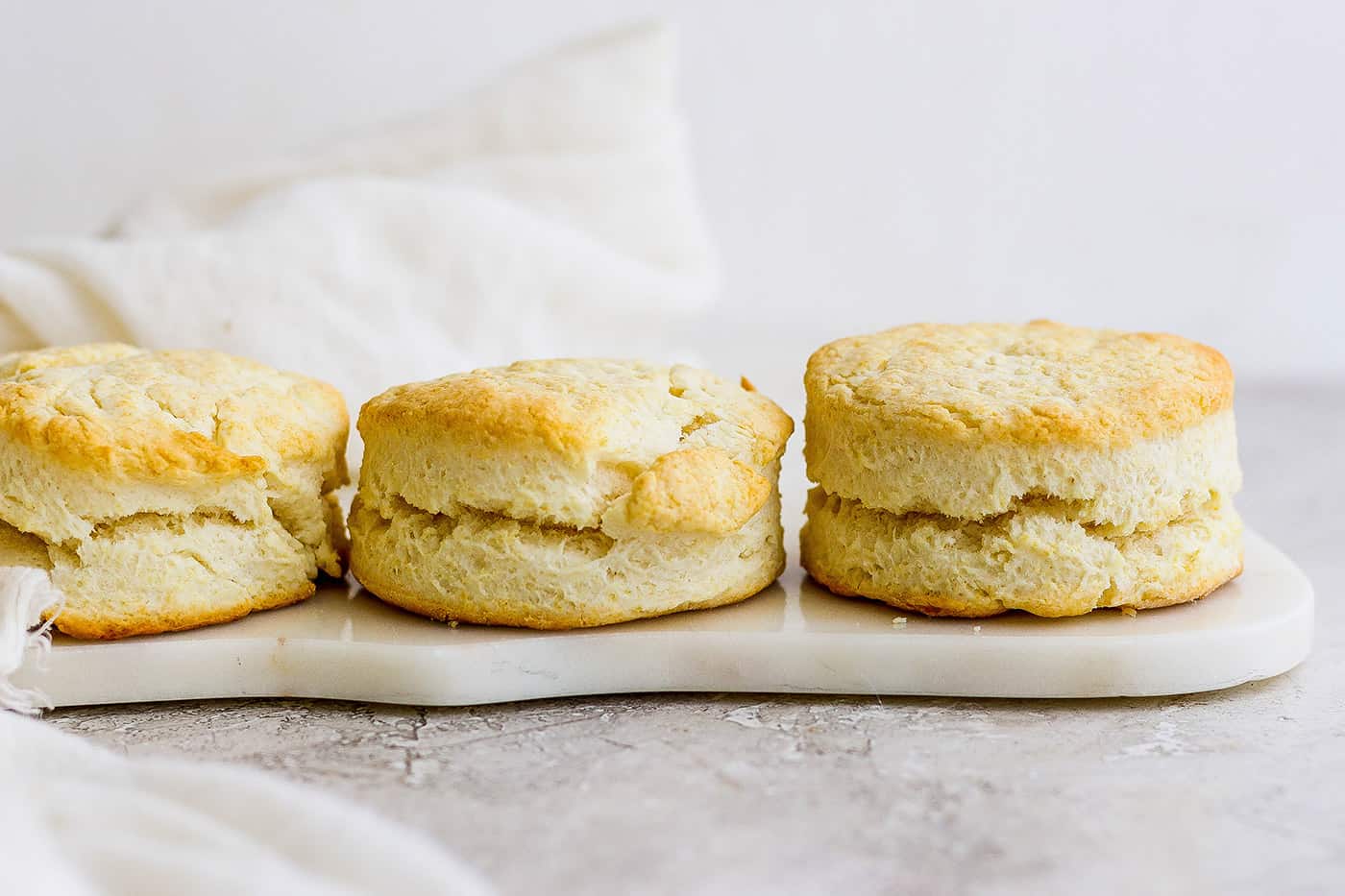 Three cream biscuits sit side by side on a white platter.