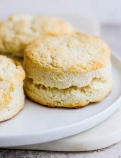 A side view of a white plate of 3 cream biscuits.