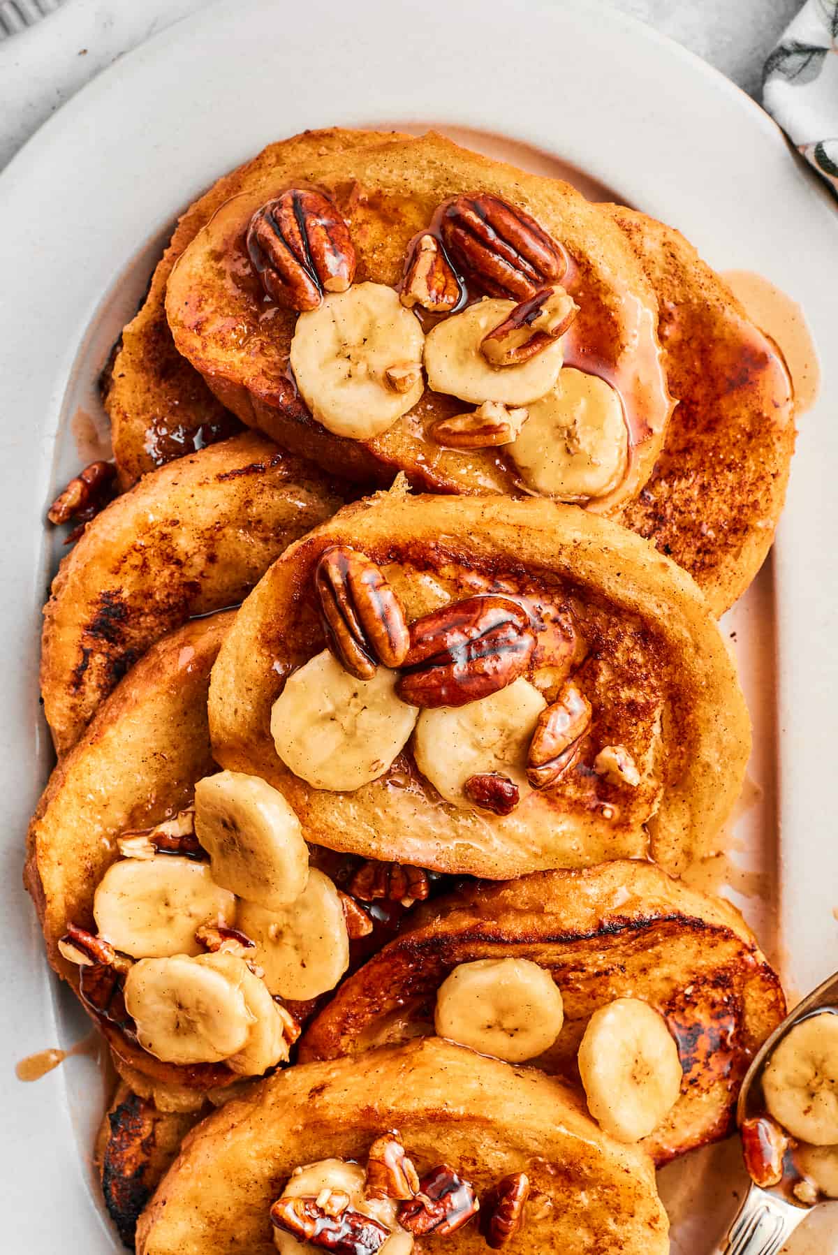 Slices of bananas foster French toast are piled on a serving platter.