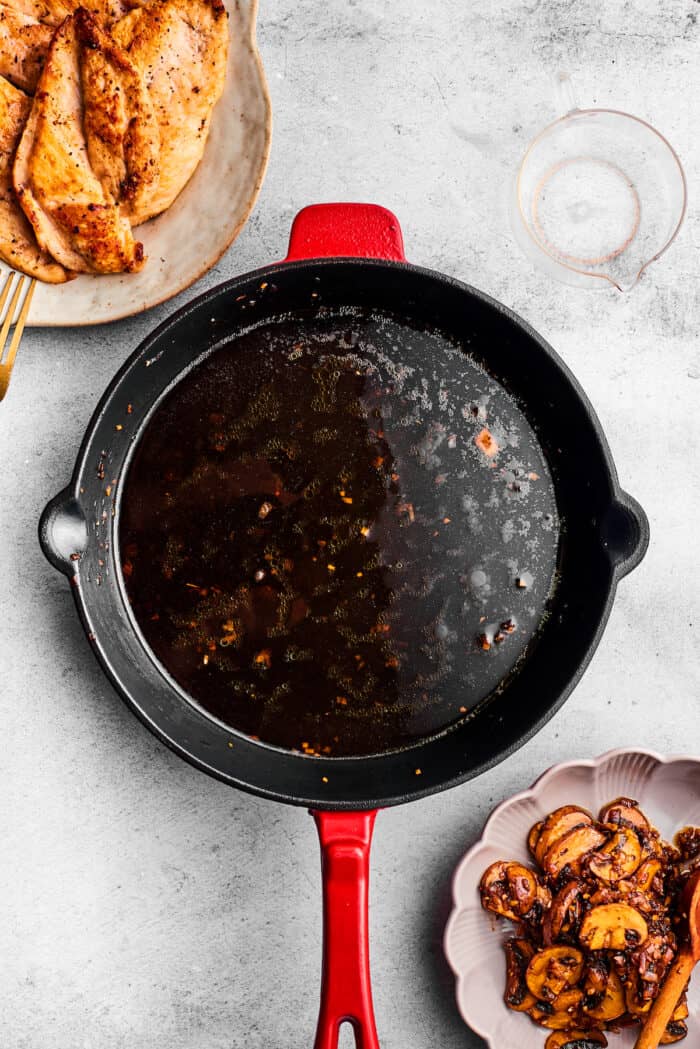 A black skillet is shown with chicken and mushrooms next to it.