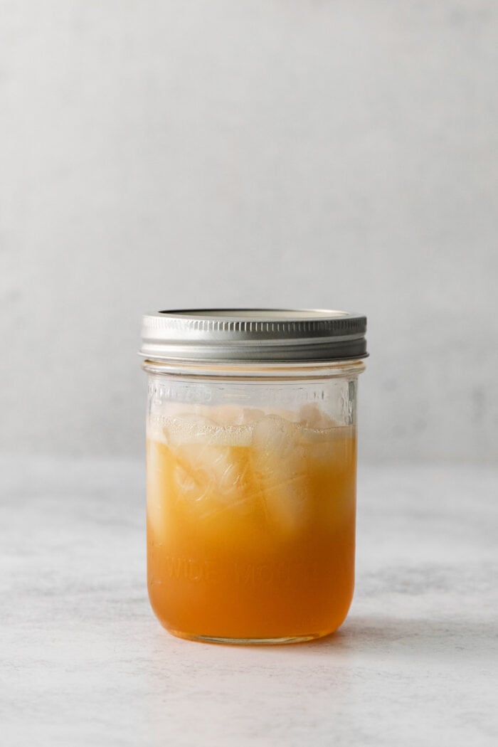 A mason jar full of amaretto sour and ice.