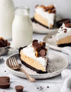 A candy-topped piece of Reeses pie is shown on a plate with more slices of pie around it.