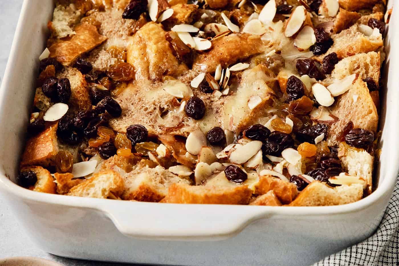 A baking dish full of capirotada topped with raisins and almonds.