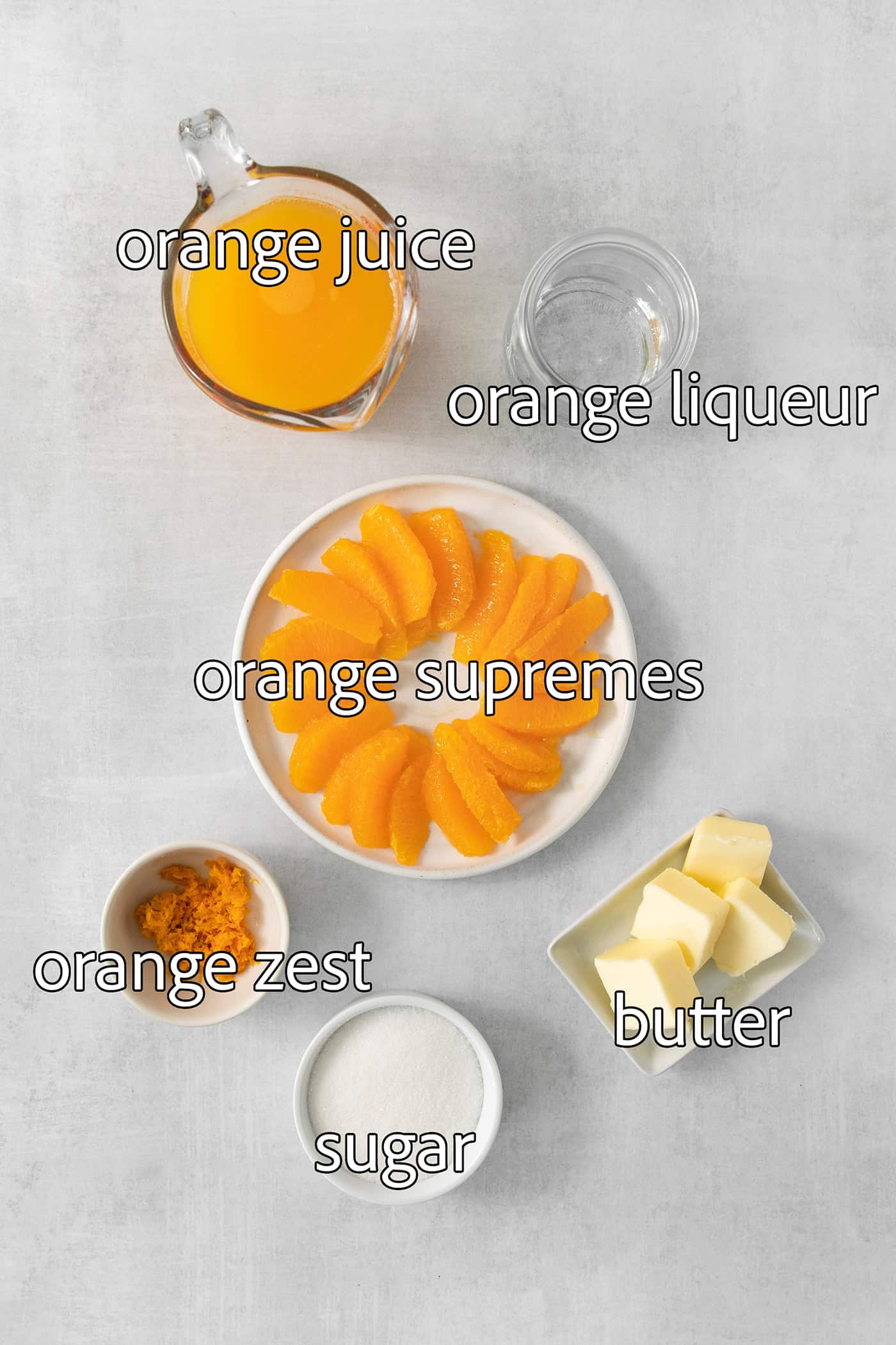 The ingredients for the orange sauce are shown labeled and portioned out: butter, orange segments, orange juice, orange zest, sugar,