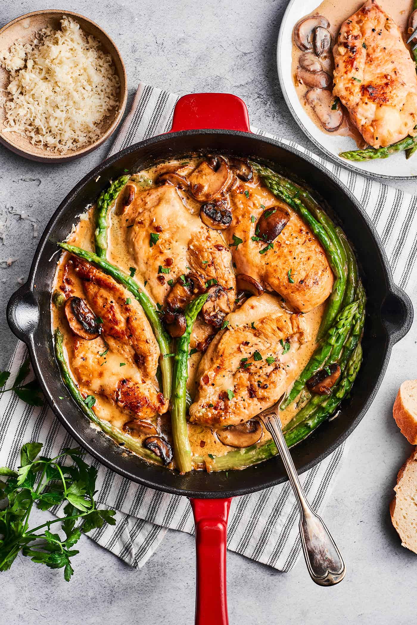 overhead photo of chicken breasts, asparagus, and mushrooms in a skillet, with Madeira sauce