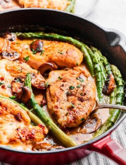 chicken breasts, asparagus, and mushrooms in a skillet, with Madeira sauce