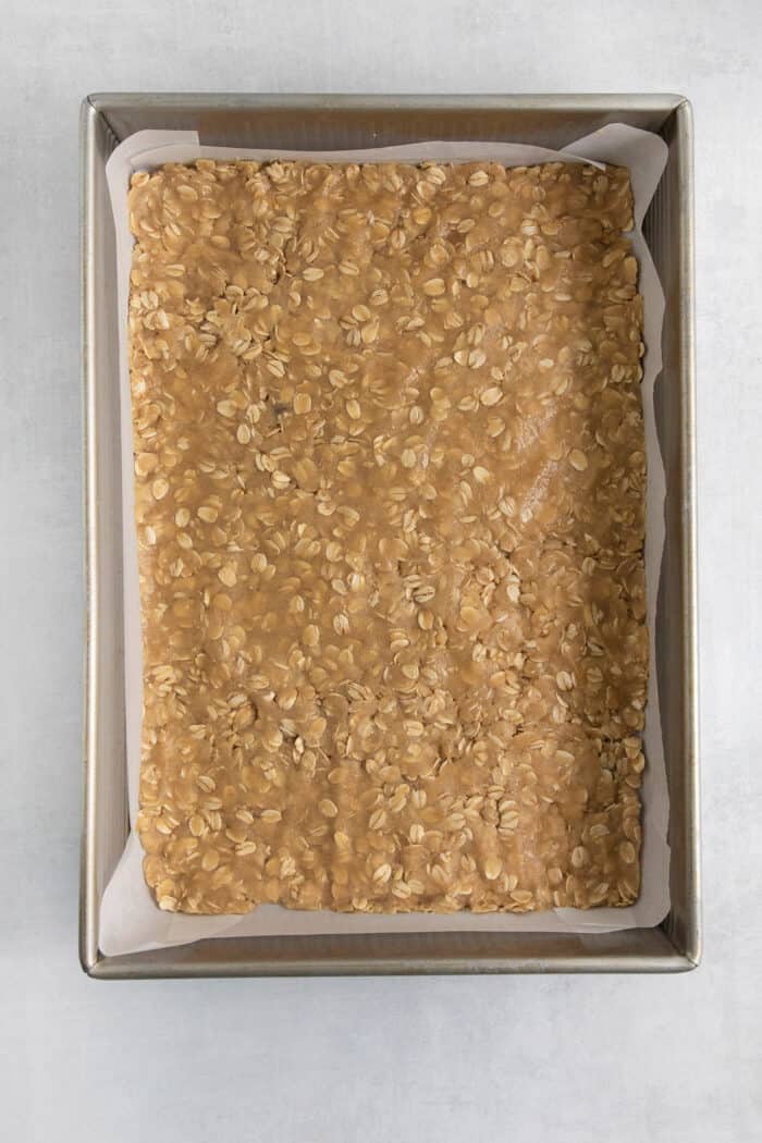 The oat shortbread layer is pressed into the baking pan.