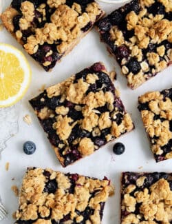 Six blueberry crumble bars on a white background.