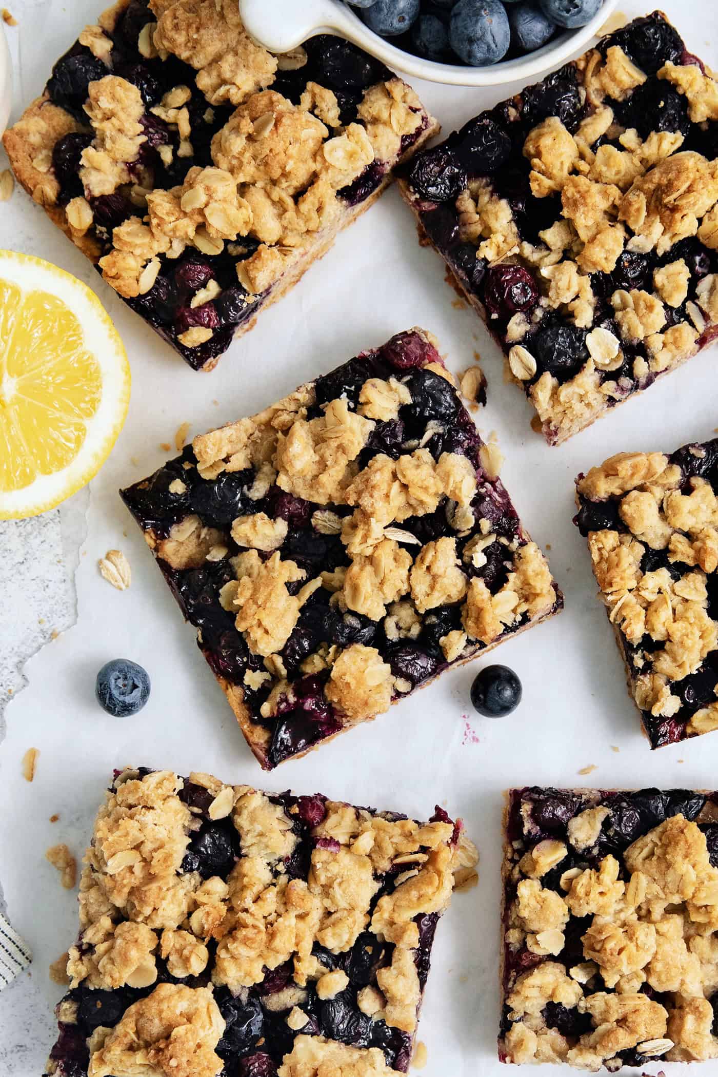Six blueberry crumble bars on a white background.