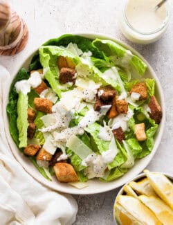 A big bowl of caesar salad topped with homemade caesar dressing.