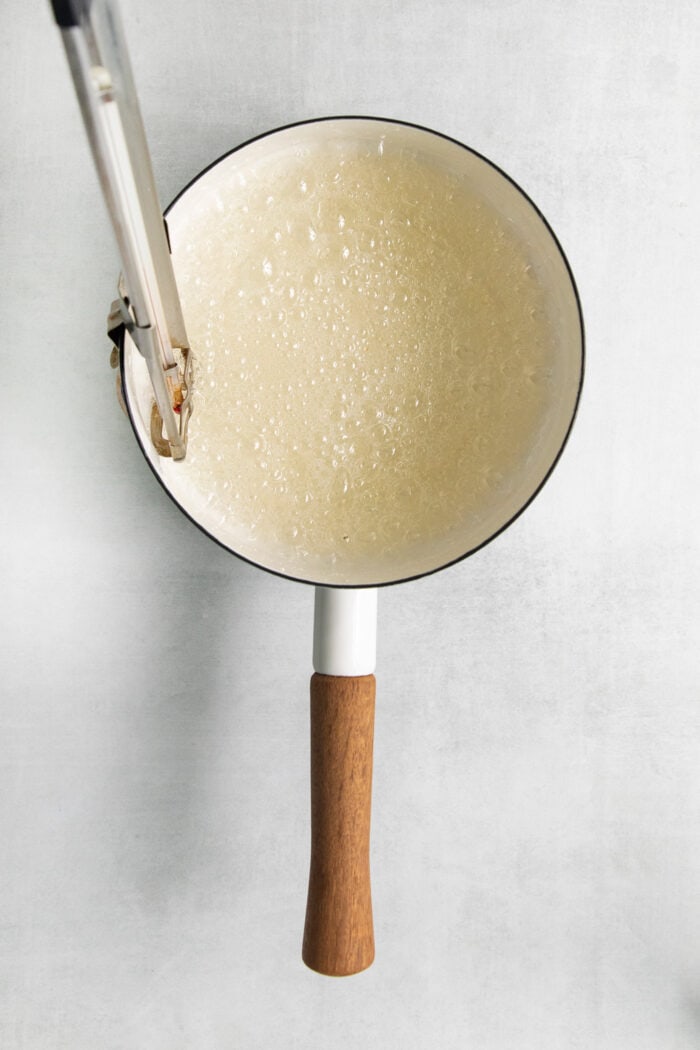 A candy thermometer is used to check the bubbling sugar syrup.