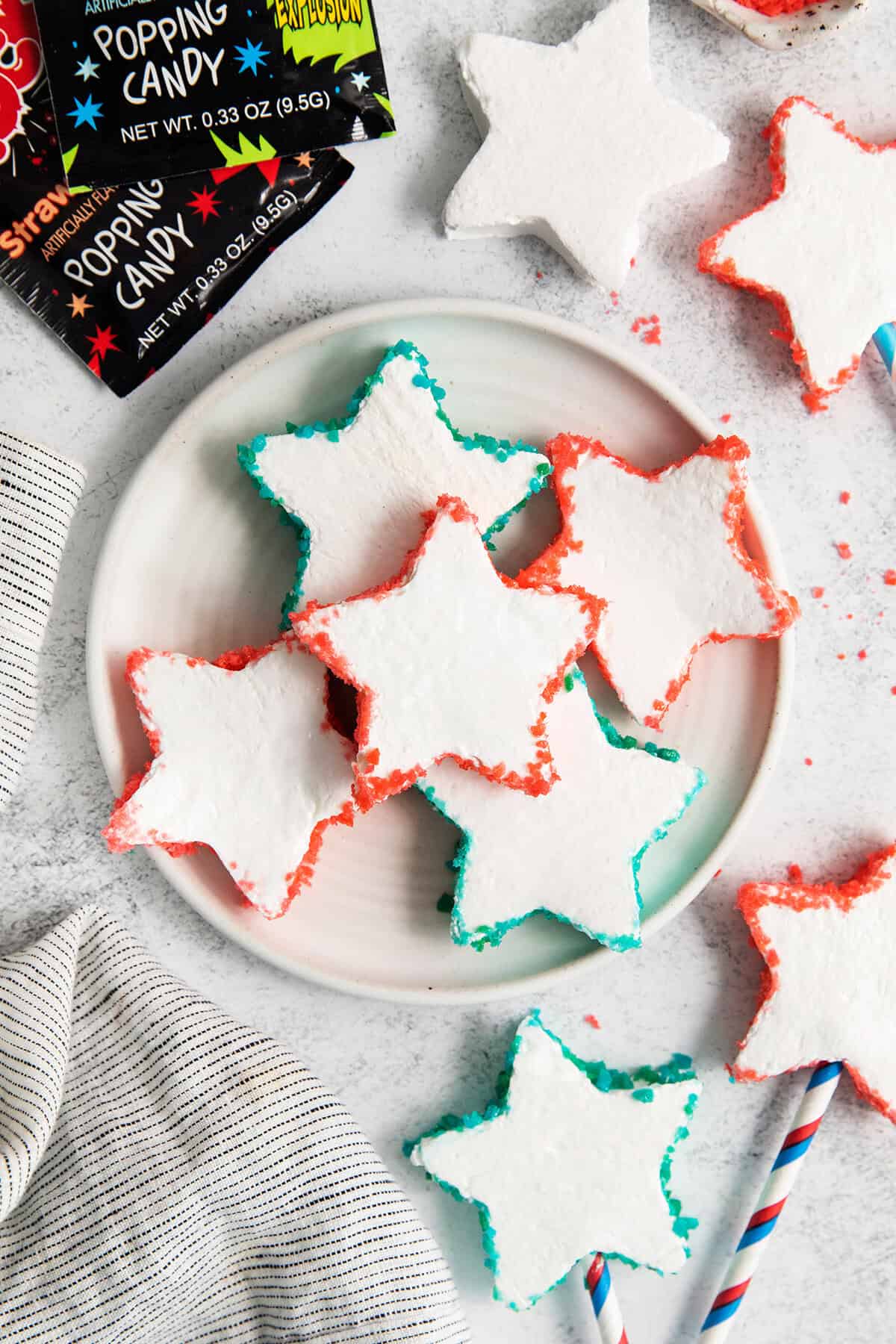 The star shaped marshmallows edged with Pop Rocks on a plate.