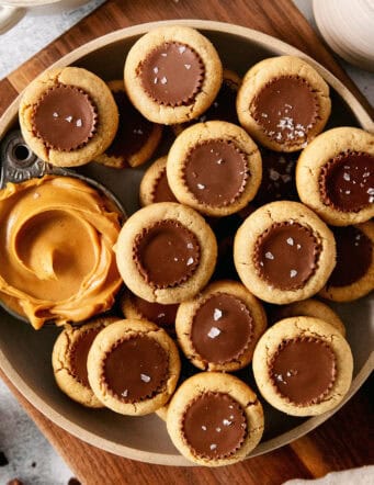 Peanut butter cup cookies with a dish of creamy peanut butter next to them are served in a bowl.
