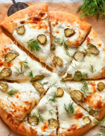 overhead photo of a whole pickle pizza cut into individual pieces