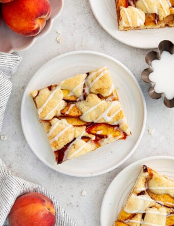 Peach bars are served on plates surrounded with whole peaches.