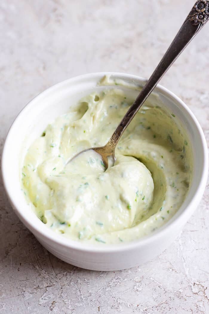 Basil mayonnaise sauce is stirred in a bowl.