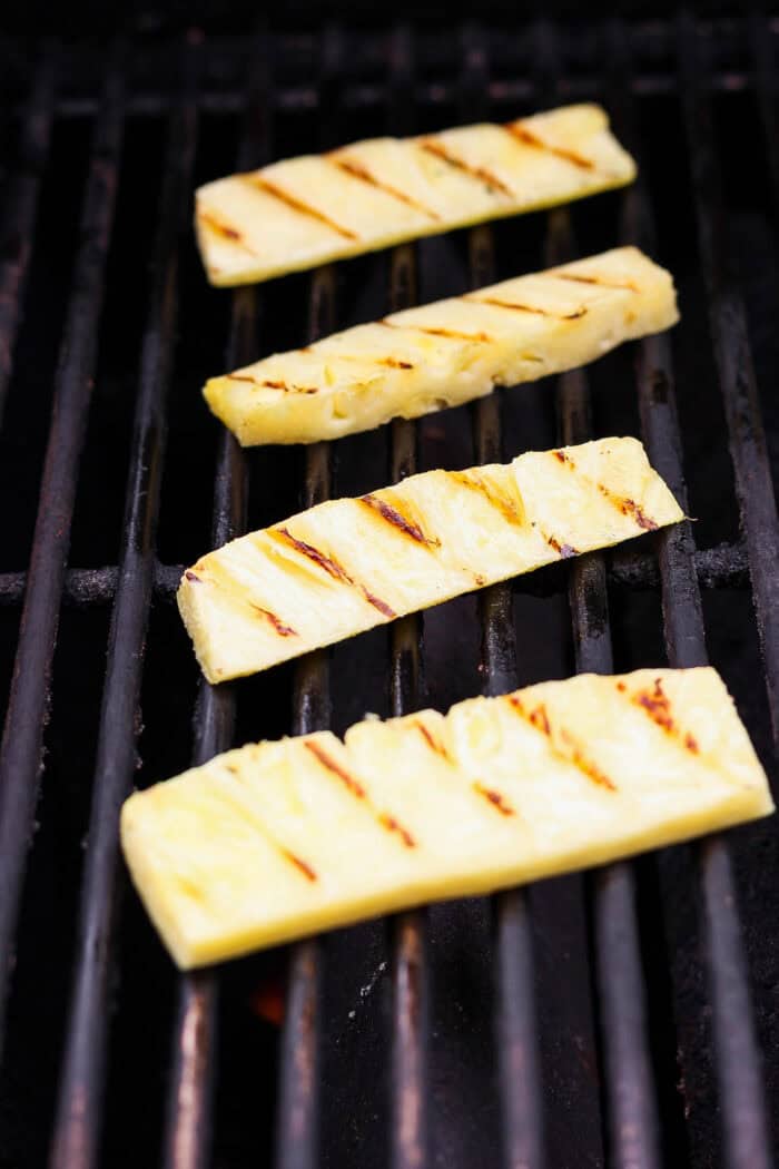 Char marks form as pineapple grills.