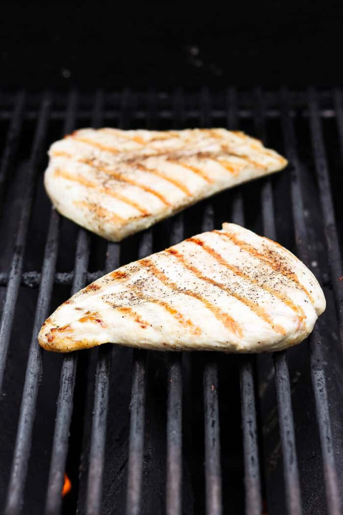 Chicken breasts cook on the grill.