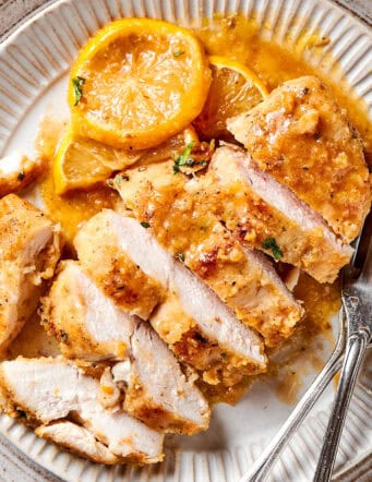 a sliced chicken breast with lemon and pepper, on a plate